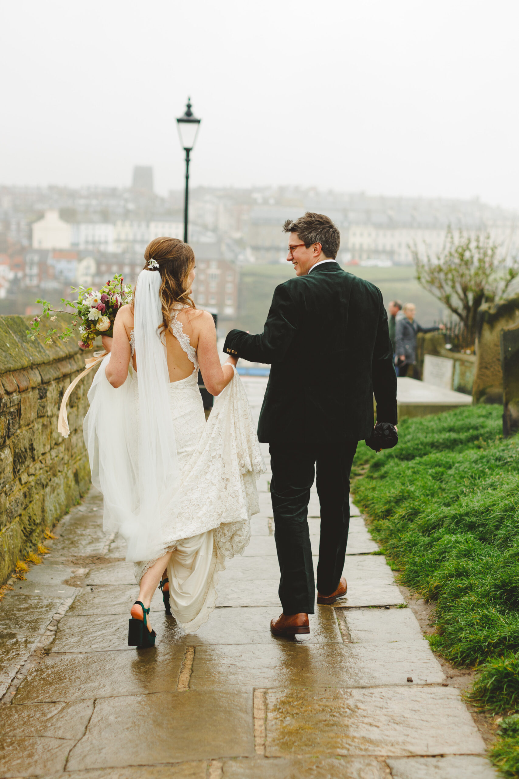Bride and groom about to walk down the 199 step sat Whitby on a rainy wedding day.